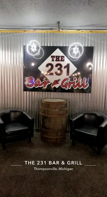 The 231 Bar & Grill sign over a whiskey barrel with lounge chairs